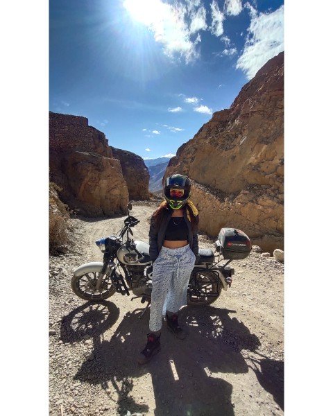 Divya with a motorcycle on a mountain road