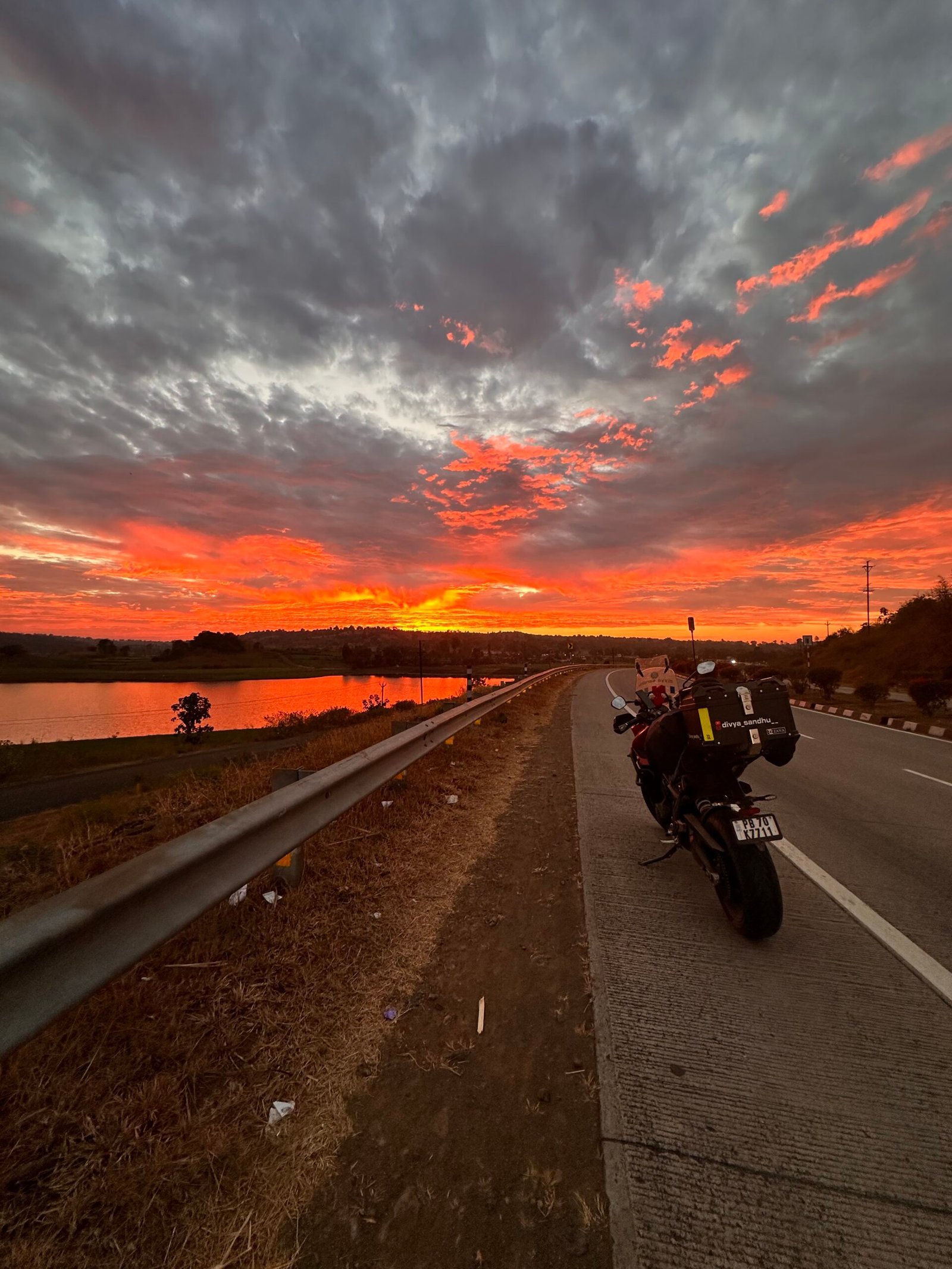 A motorcycle and the open road under a dramatic sunset